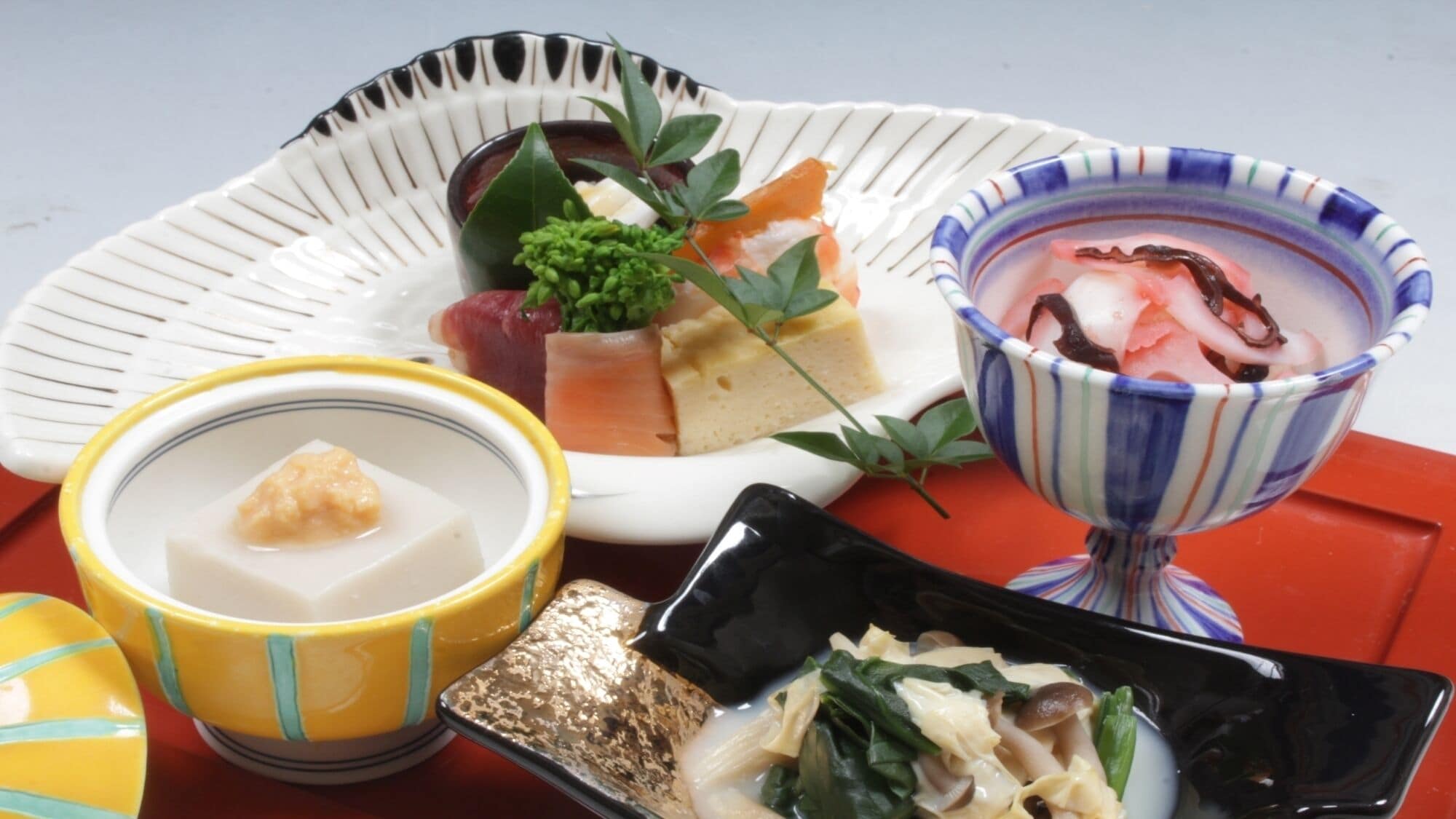 Diverse Japanse gerechten, waaronder sushi, een kom soep en een klein schaaltje ingelegde groenten.
