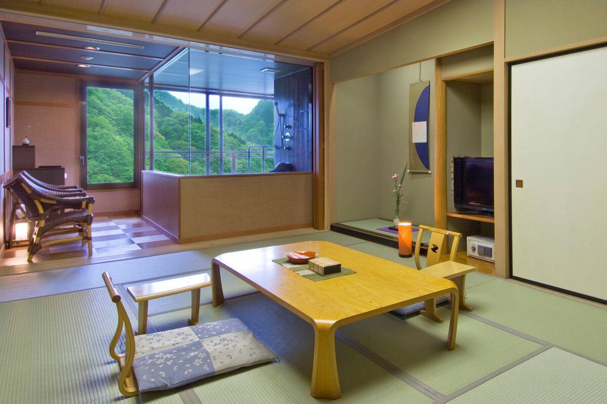 A traditional Japanese-style room with tatami flooring, a low wooden table, and a television.