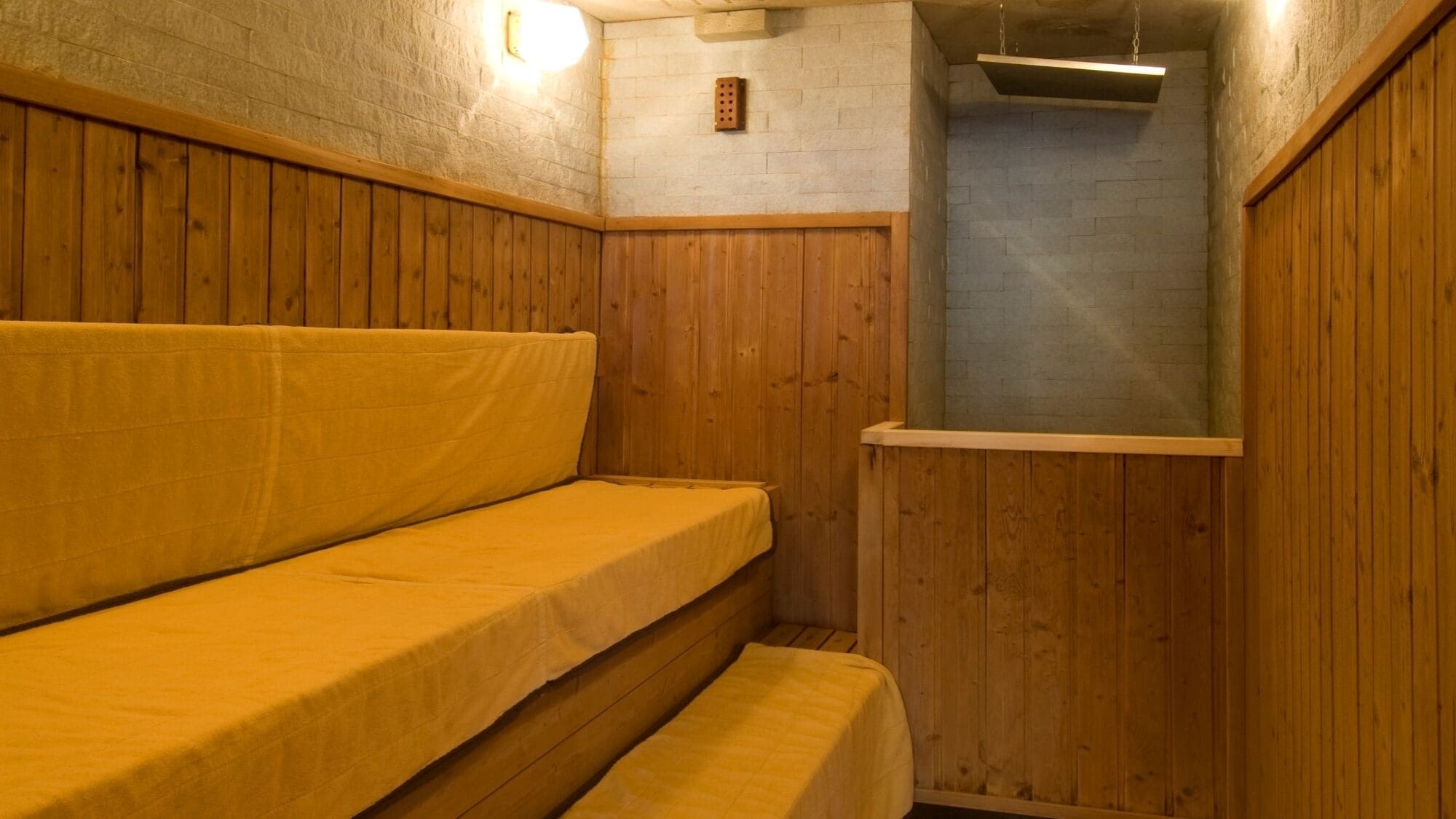 Un banco de madera con una cubierta amarilla en una habitación con paredes de piedra y techo de madera.