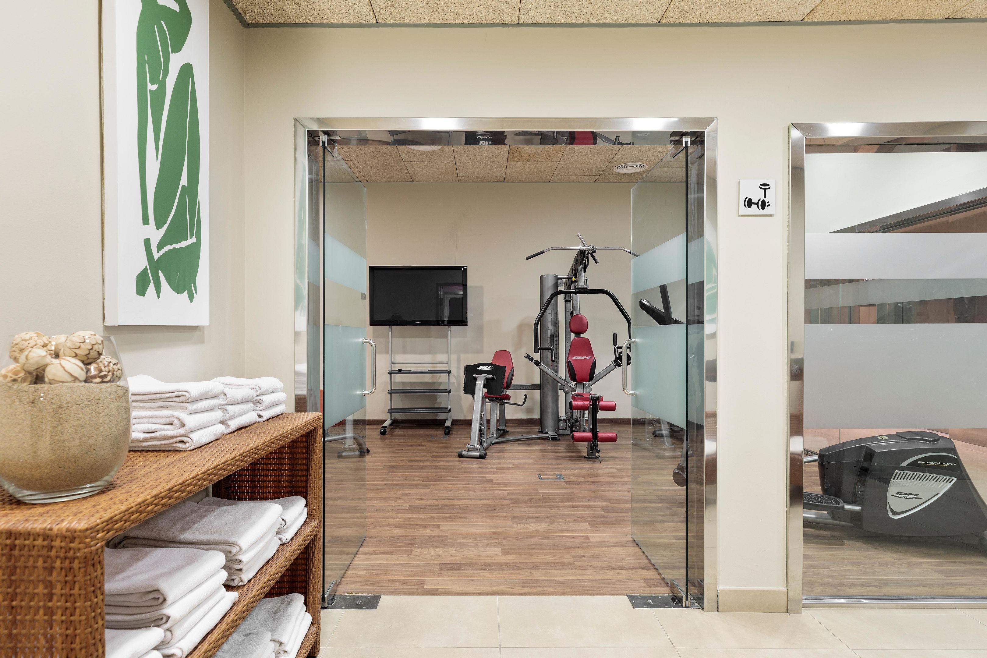 Une salle de sport équipée de matériel d’exercice, d’un téléviseur et d’un panneau fixé au mur.