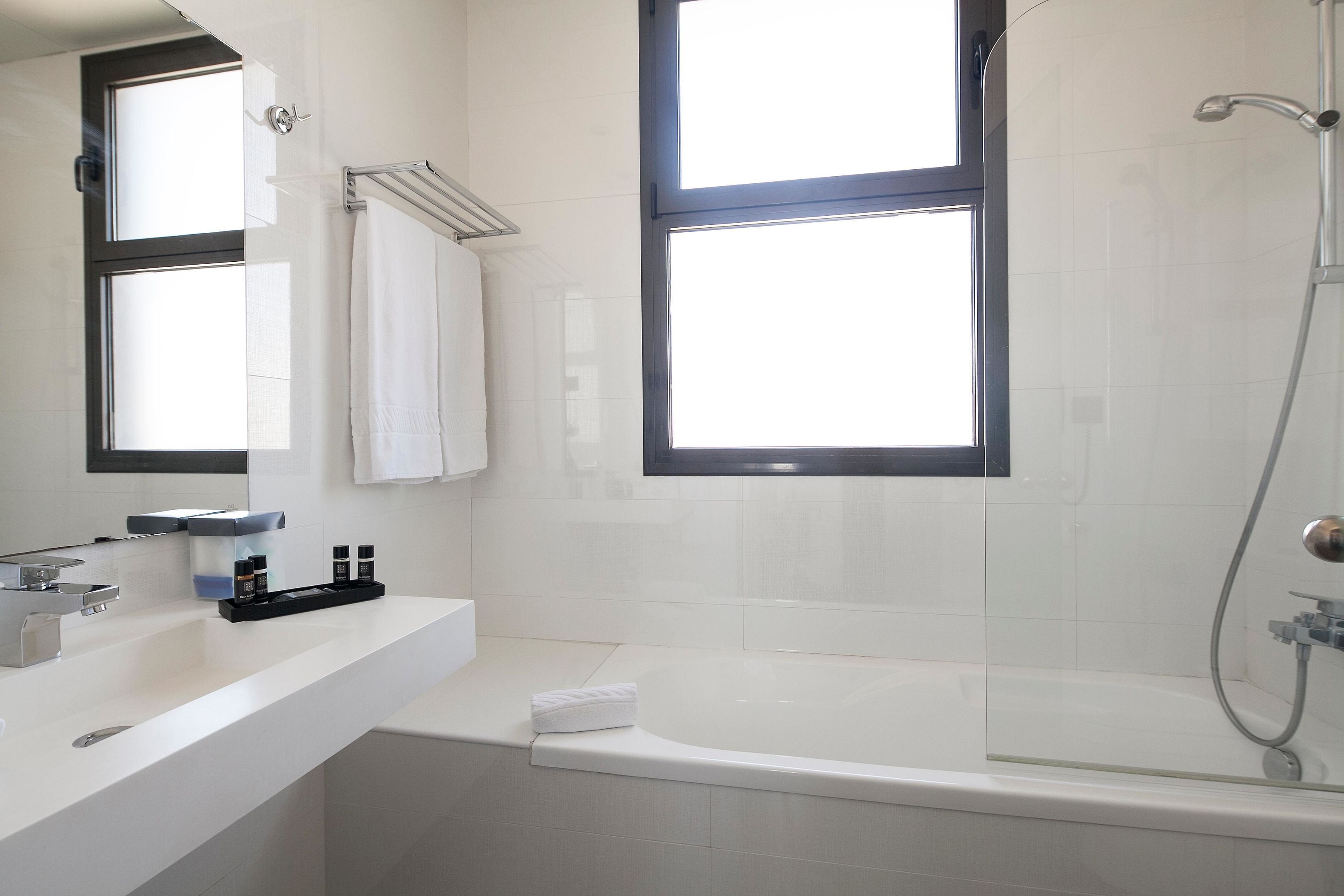 Un baño moderno con bañera, ducha y un ventanal grande.