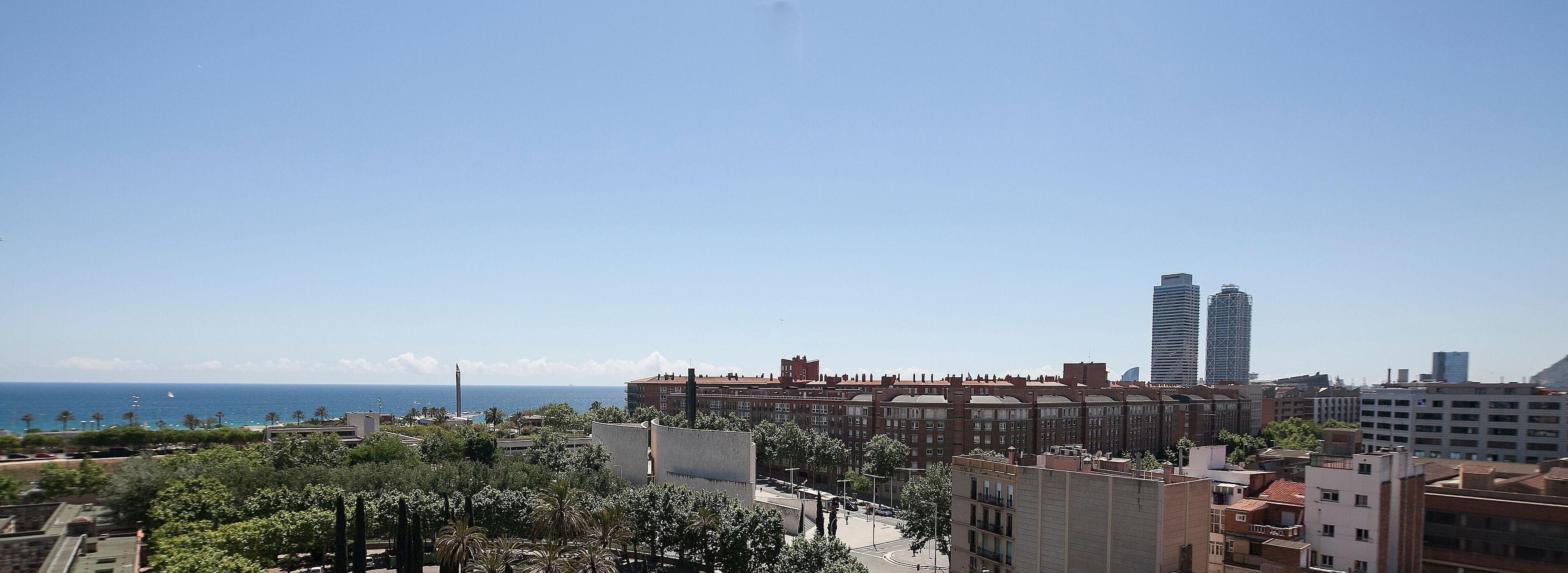 Un paisaje urbano costero con edificios modernos, cielo despejado y vista al mar.