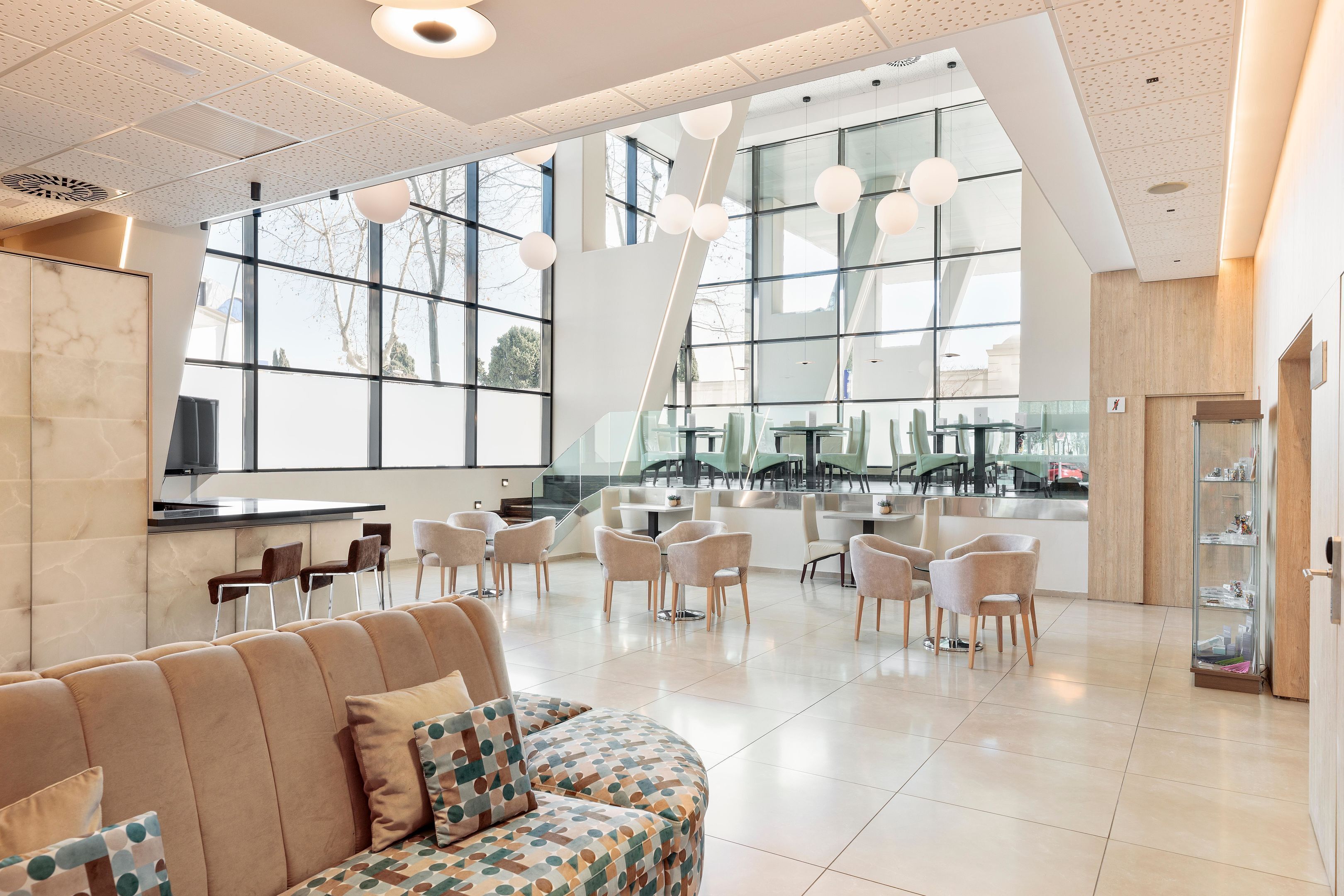 A modern interior with a seating area, large windows, and a kitchen counter.