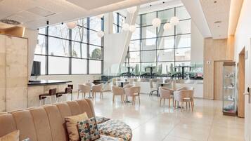 A modern interior with a seating area, large windows, and a kitchen counter.