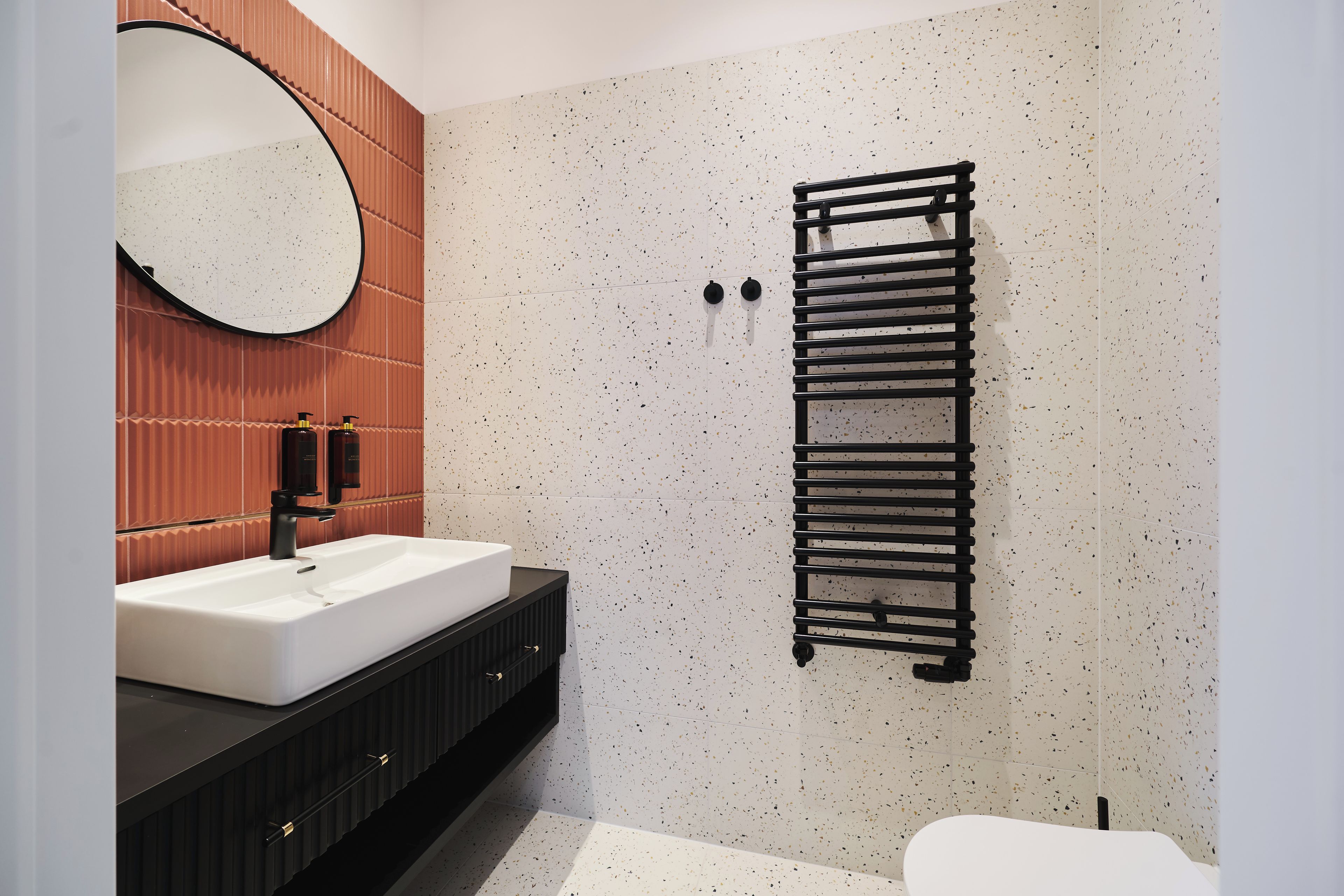 A modern bathroom with a white sink, black vanity, and a towel rack.