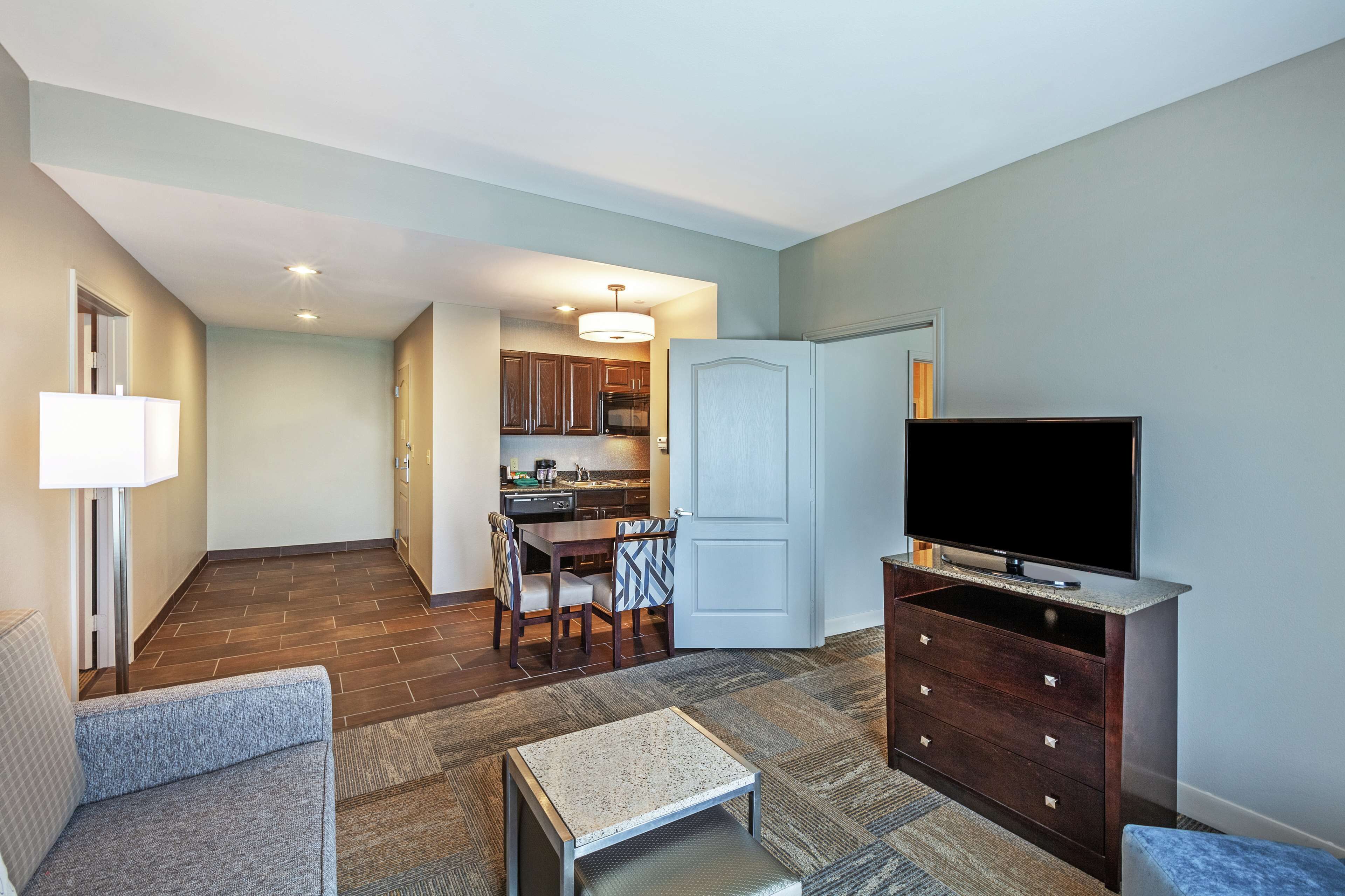 A compact living space with a dining area, kitchenette, and a TV on a wooden cabinet.