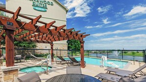 A hotel pool area with lounge chairs, a pergola, and a sign for Homewood Suites Hilton. - Homewood Suites by Hilton Waco (Waco)