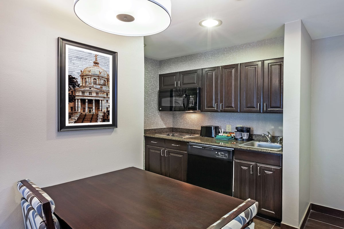 A modern kitchen with dark wooden cabinets, a black microwave, and a dishwasher.