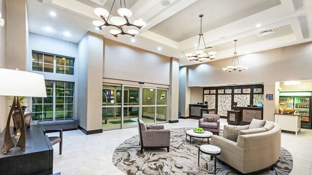 A spacious lobby with a round seating area, a reception desk, and a view of the outside through large windows. - Homewood Suites by Hilton Waco (Waco)