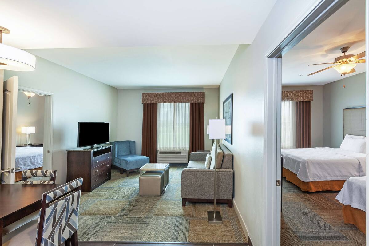 A hotel room with a bed, a desk, a chair, a television, and a sofa.