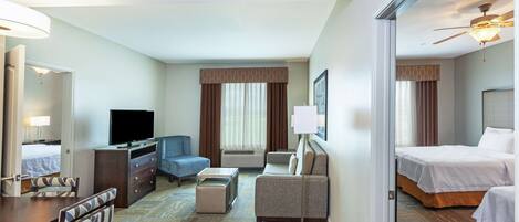 A hotel room with a bed, a desk, a chair, a television, and a sofa.