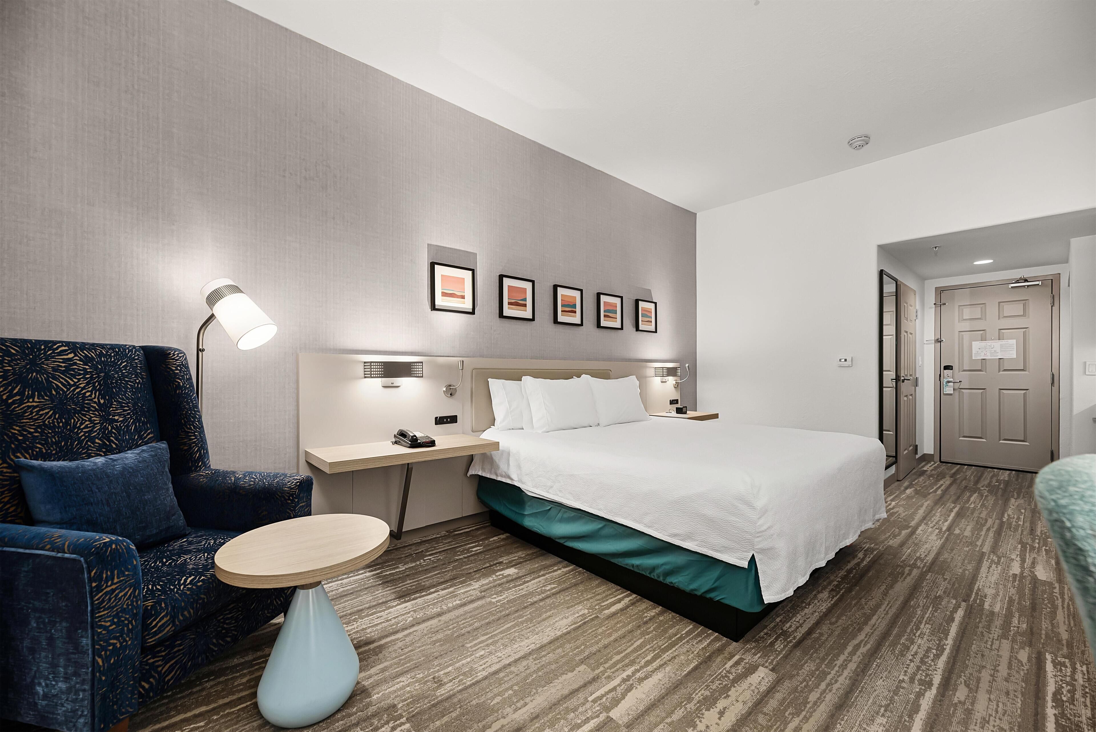 Een hotelkamer met een bed, een bureau, een stoel en een ronde tafel.