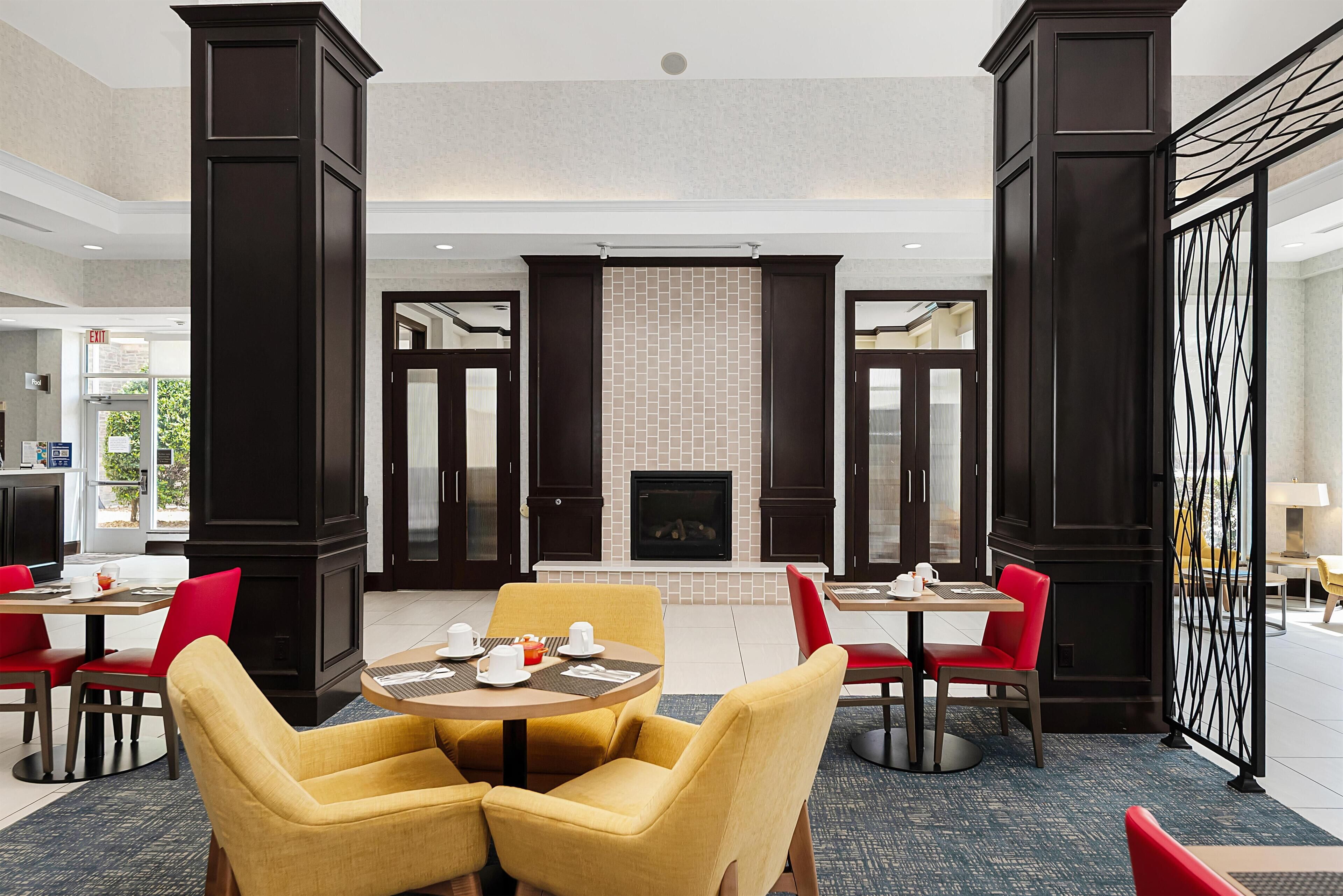 A hotel lobby with a fireplace, multiple seating areas, and a view of the outside.