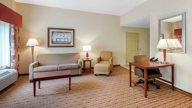 Habitación de hotel con sofá, sillón, escritorio y lámparas.
