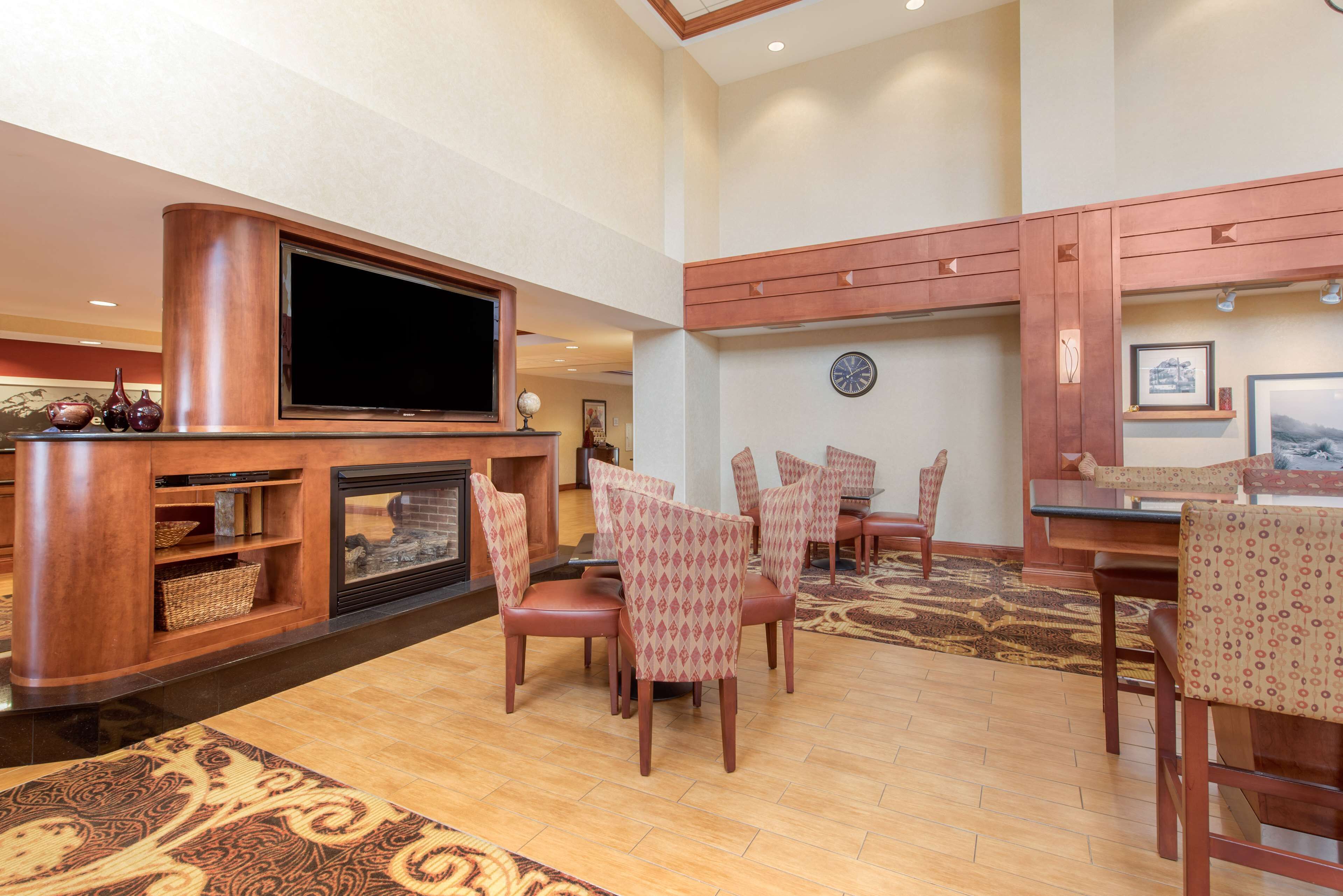 A spacious living area with a large flat-screen TV, a fireplace, and a dining area with patterned chairs and a wooden table.
