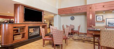 A spacious living area with a large flat-screen TV, a fireplace, and a dining area with patterned chairs and a wooden table.