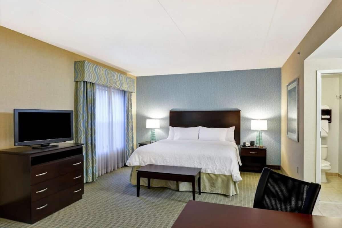 Une chambre d’hôtel comprenant un lit, des tables de chevet, une télévision, un bureau et une chaise.