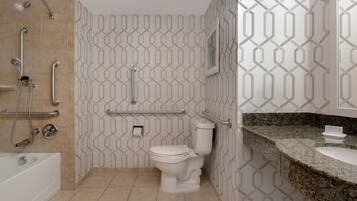 Un baño moderno con inodoro blanco, ducha con barras de apoyo y encimera de granito.