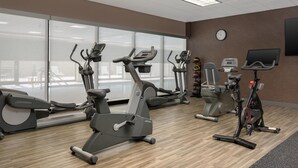 Un gimnasio con bicicletas estáticas, cintas de correr y una máquina de pesas.