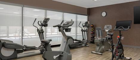 A gym with stationary bikes, treadmills, and a weight machine.