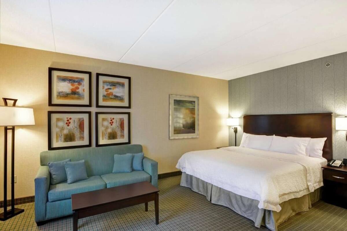 Une chambre d’hôtel avec un lit, un canapé, une table basse et des œuvres d’art murales.