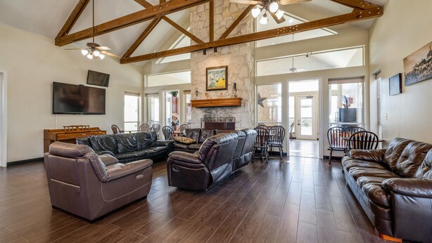 A spacious living room with a sectional sofa, a fireplace, and a high ceiling with exposed beams. - Mountain Star Lodge (Austin)