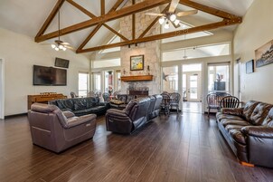 A spacious living room with a sectional sofa, a fireplace, and a high ceiling with exposed beams.