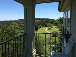 A balcony with a view of a green landscape and a path.