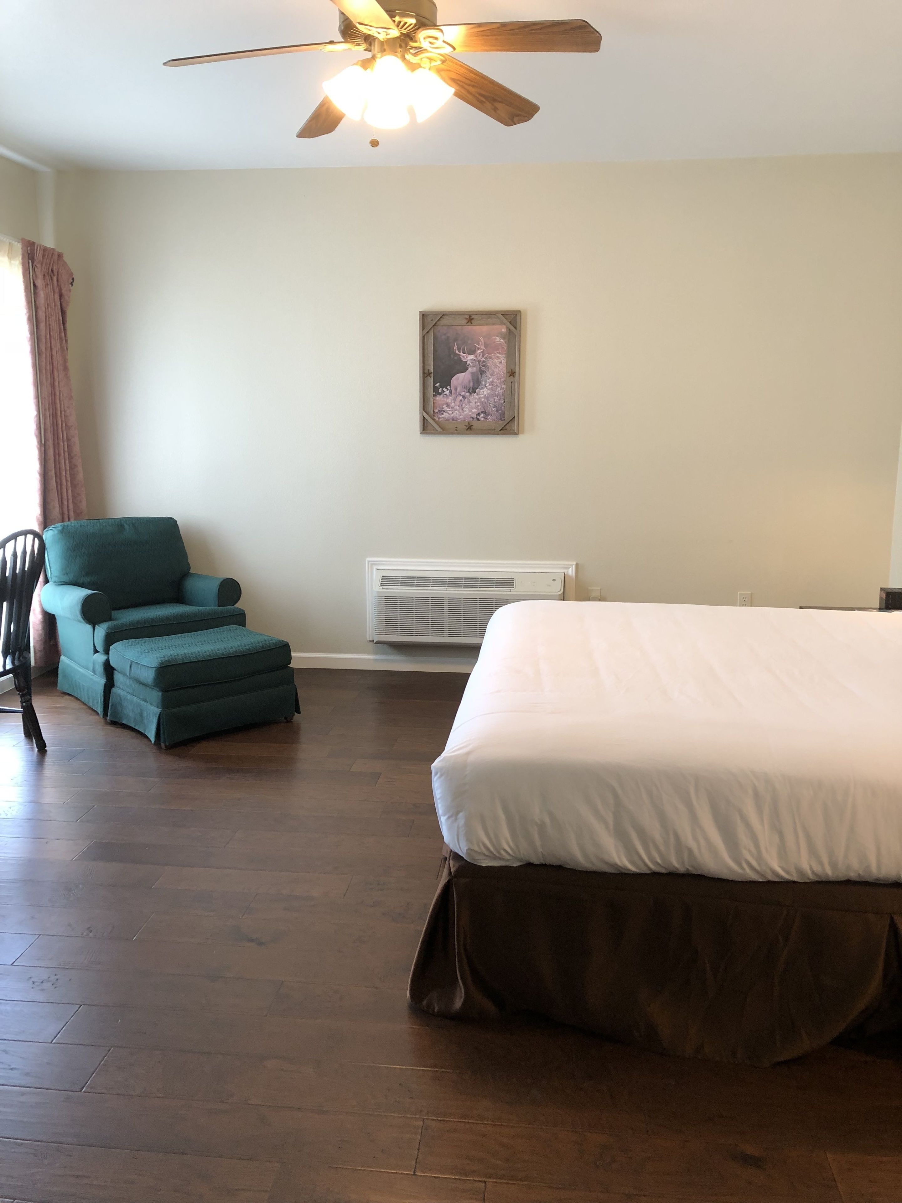 Une chambre à coucher avec un lit, une chaise, un radiateur et un ventilateur de plafond.
