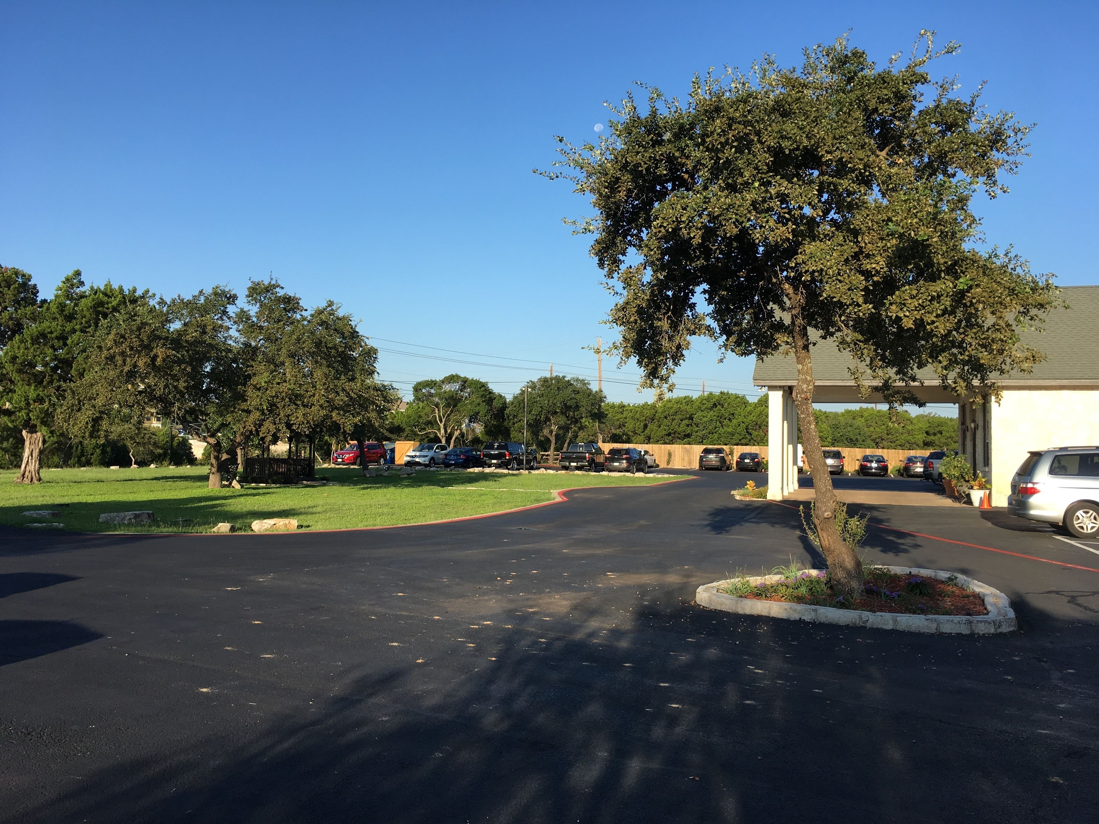 A parking lot with cars, a building, and trees.