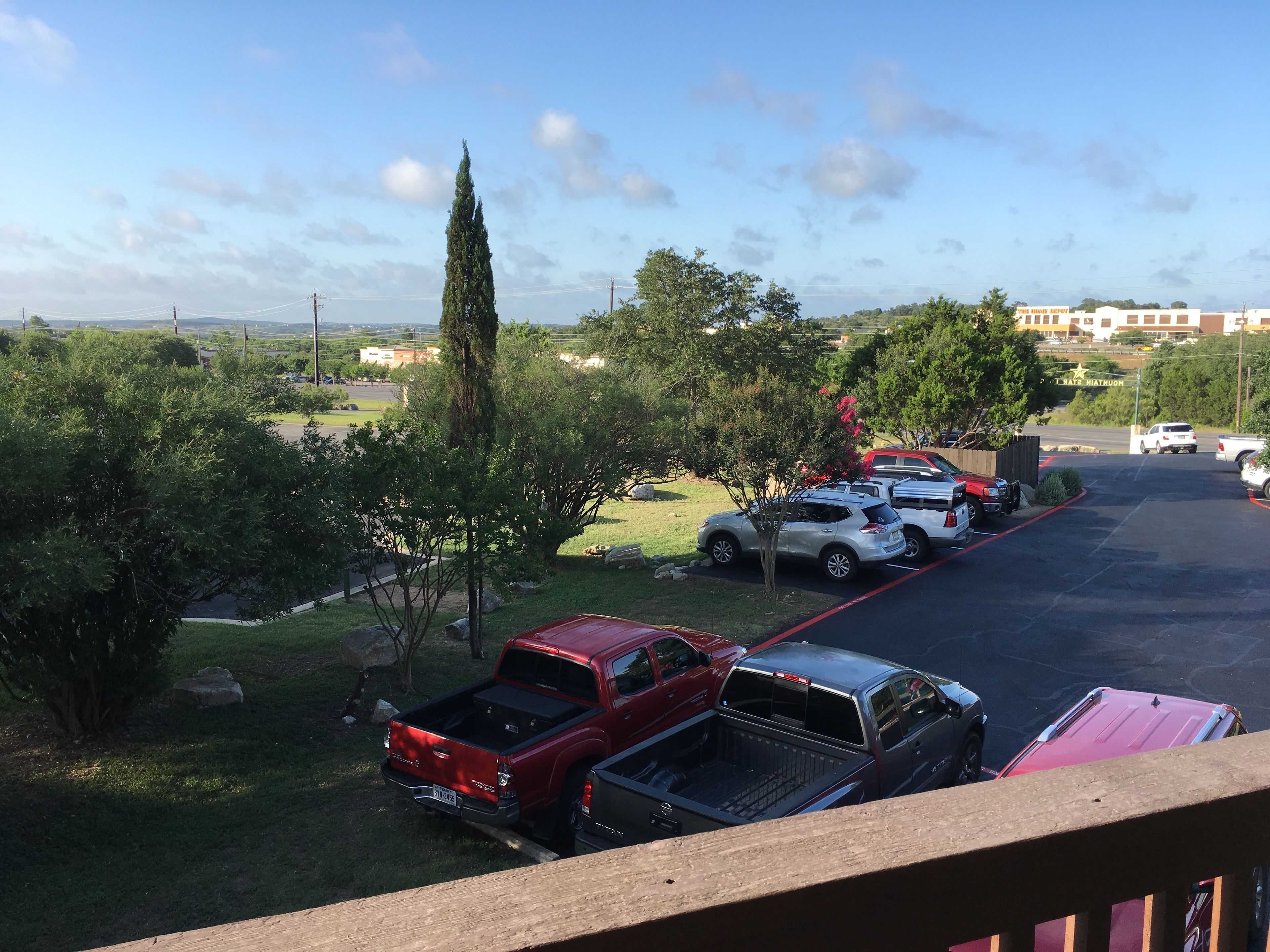 A parking lot with several vehicles, including a red pickup truck and a silver SUV.