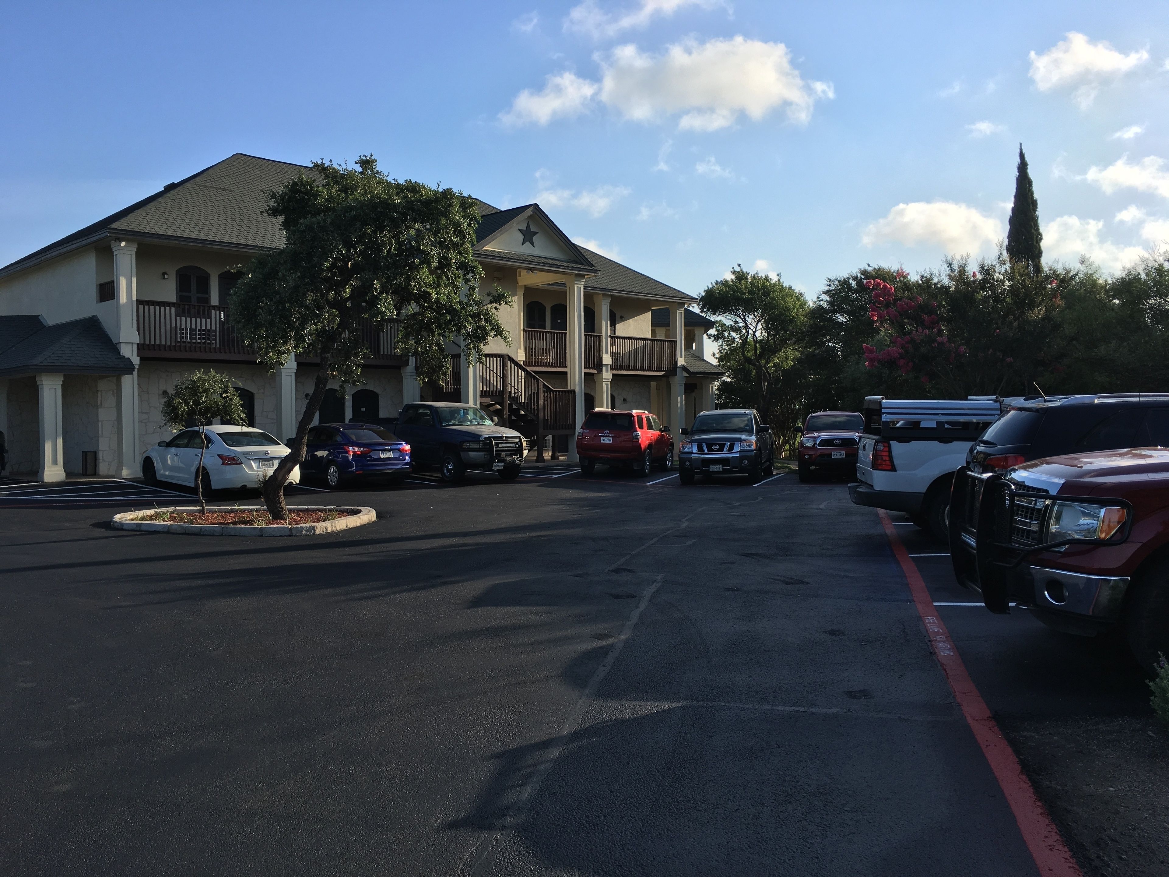 A parking lot with several cars and a building with a balcony and a star on the roof.