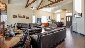 A spacious living room with leather sofas, a wooden dining table, and a kitchen in the background. - Mountain Star Lodge (Austin)