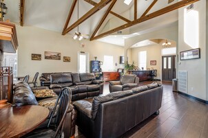 A spacious living room with leather sofas, a wooden dining table, and a kitchen in the background.
