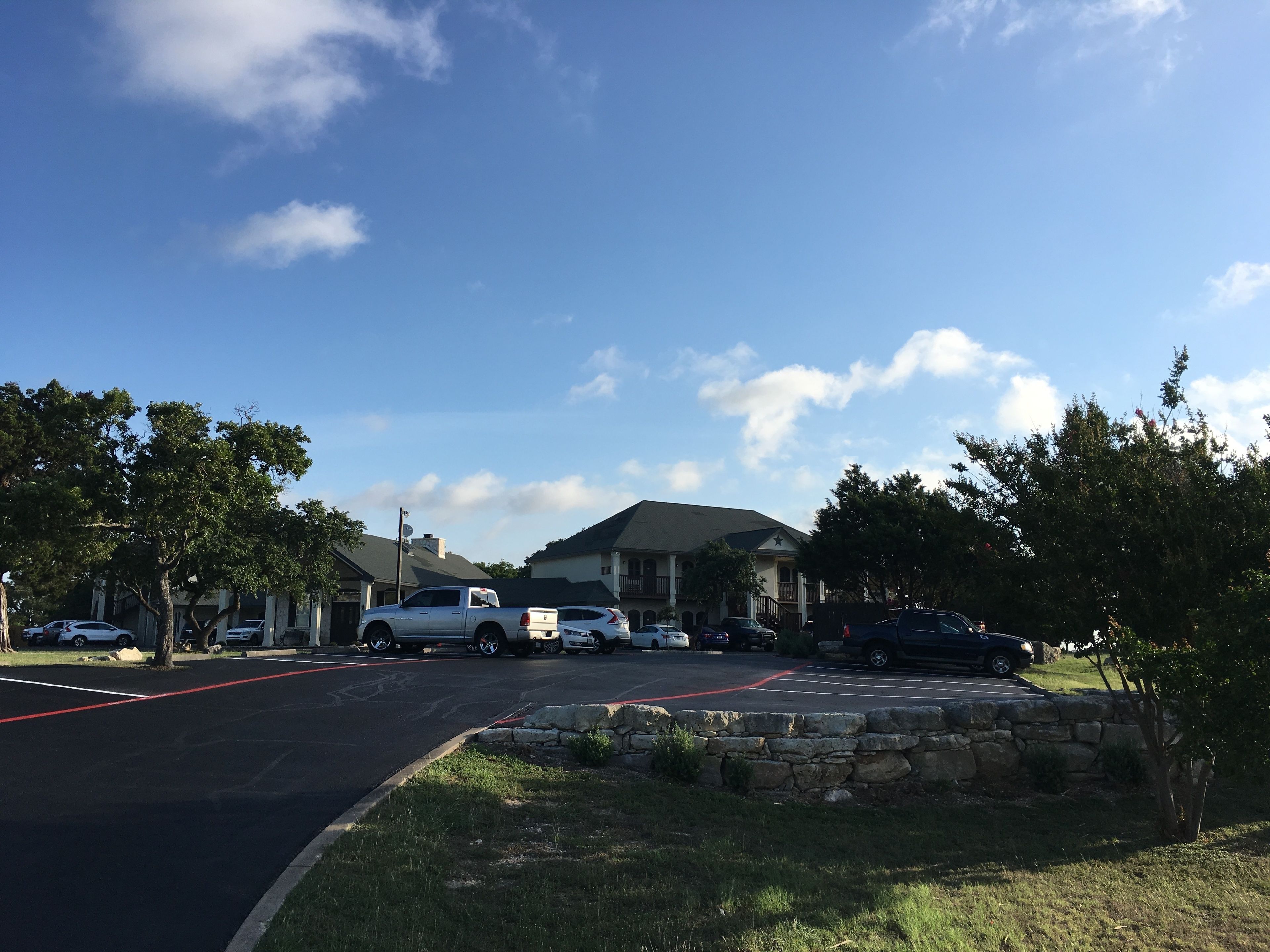 A parking lot with several cars, a stone wall, and a building with a star on the roof.