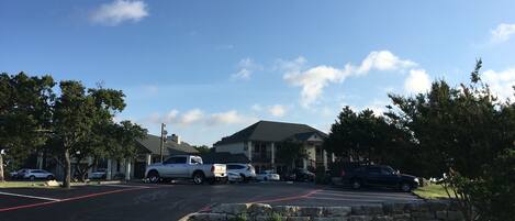 A parking lot with several cars, a stone wall, and a building with a star on the roof.