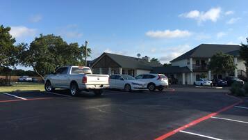 A parking lot with several vehicles, including a white pickup truck and a white sedan.