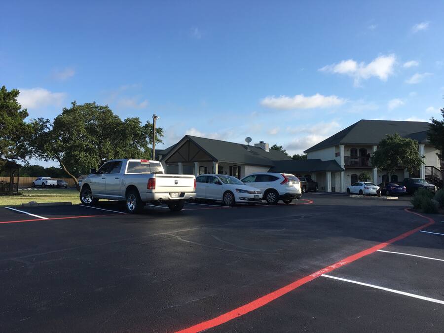 A parking lot with several vehicles, including a white pickup truck and a white sedan.