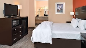 Habitación de hotel con cama, televisor, escritorio y baño a la vista.