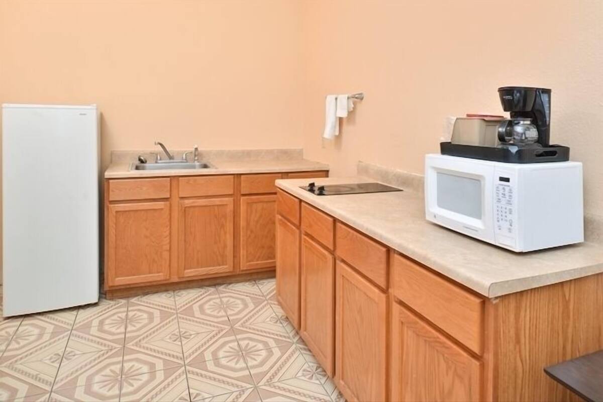 A kitchen with wooden cabinets, a sink, a microwave, and a coffee maker.