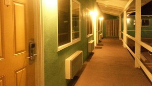 A hallway with green walls, white doors, and a radiator. - Villa Motel (San Luis Obispo)
