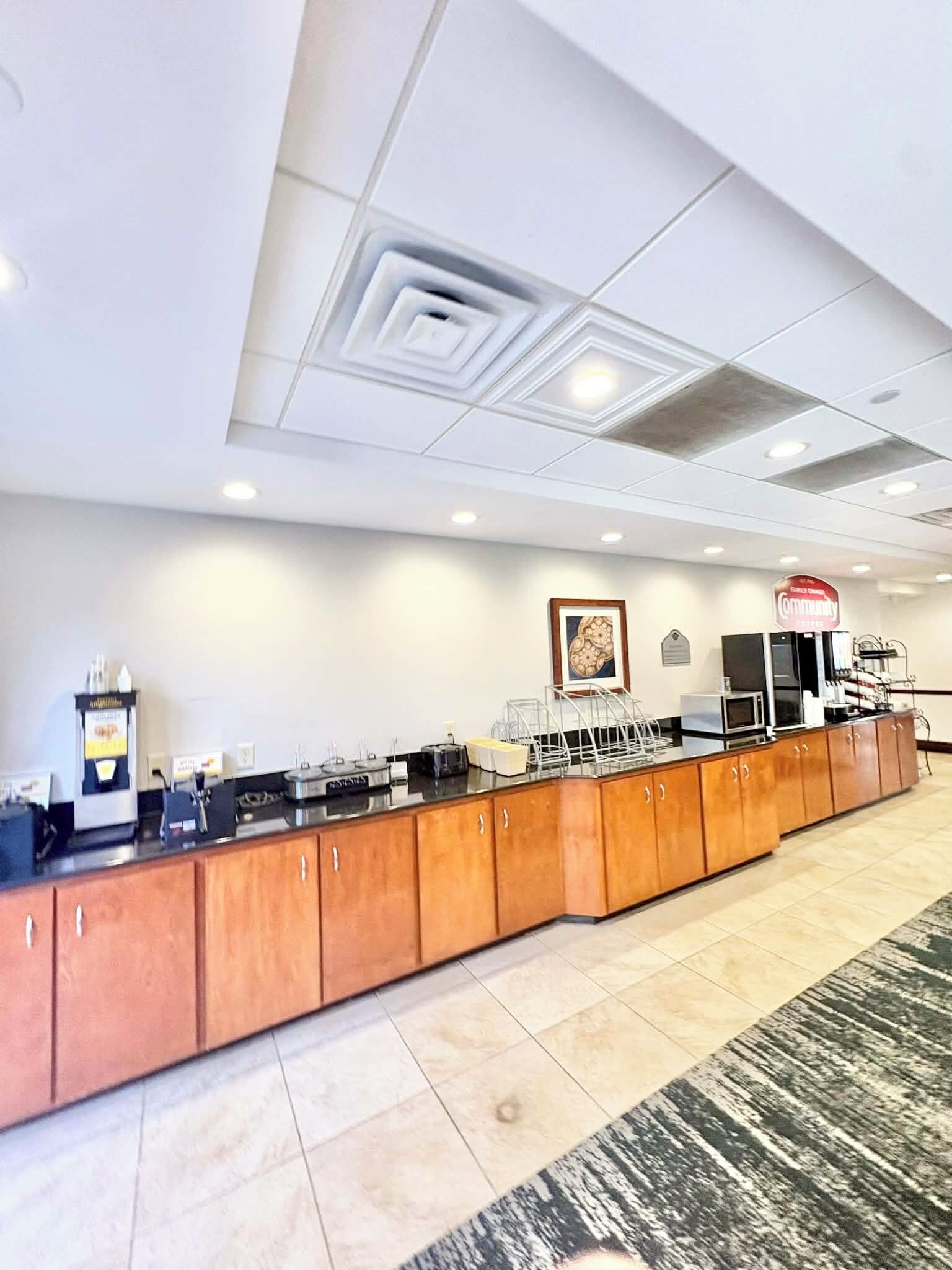 A hotel reception area with a long counter, a coffee machine, and a sign that reads "Community."