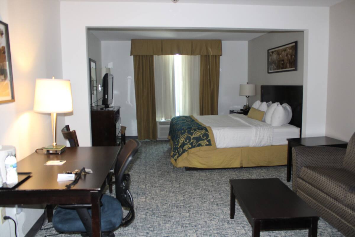 A hotel room with a bed, a desk, a chair, a sofa, and a coffee table.
