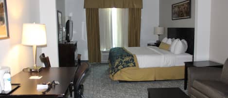 Habitació d'hotel amb un llit, escriptori, cadira, sofà i taula de cafè.