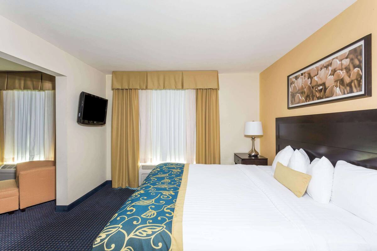 A hotel room with a bed, a TV, a desk, and a chair.