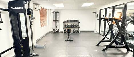 A gym with Cybex equipment, a weight rack, and a bench press.