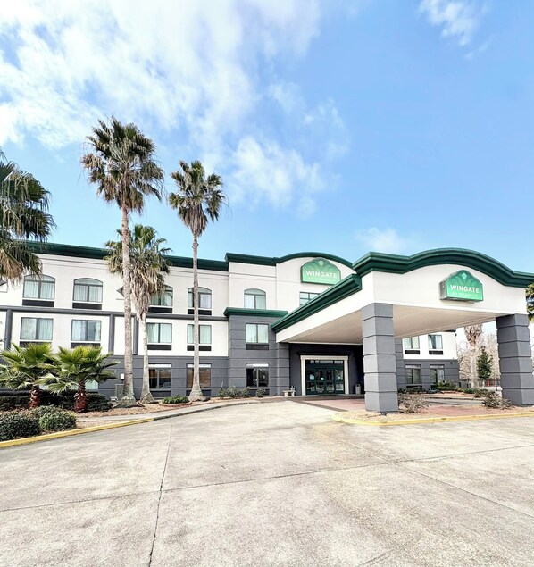 Un hotel Wingate de diseño moderno, con una entrada amplia y palmeras.