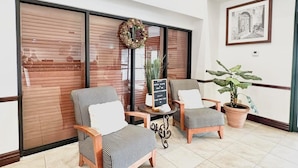 A seating area with two striped chairs and a small table, a potted plant, and a framed picture on the wall. - Wingate by Wyndham Houma LA (Houma)