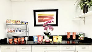 A kitchen with white cabinets, a black countertop, and various food items. - Wingate by Wyndham Houma LA (Houma)