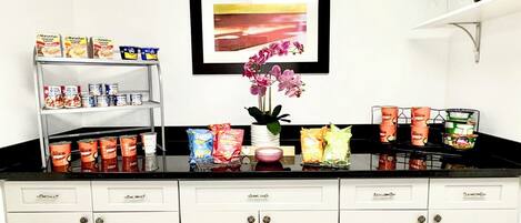 A kitchen with white cabinets, a black countertop, and various food items.